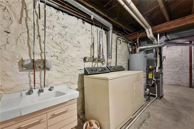 washroom featuring washer and clothes dryer, gas water heater, sink, and heating unit