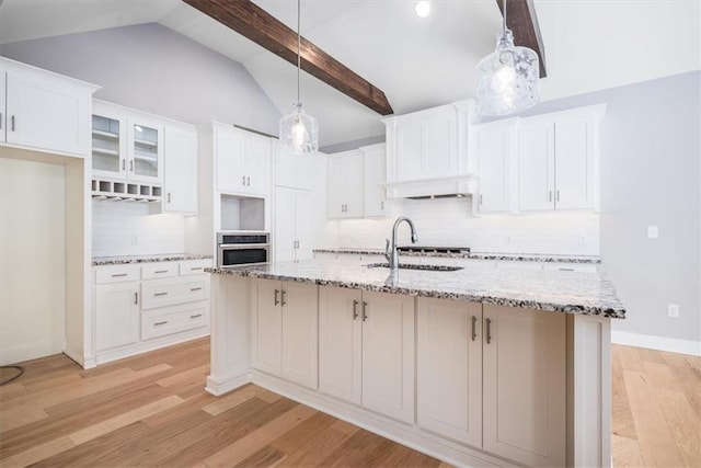 kitchen with white cabinets, stainless steel oven, and hanging light fixtures