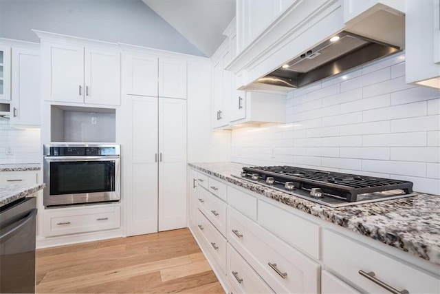 kitchen with lofted ceiling, white cabinets, light hardwood / wood-style flooring, custom range hood, and stainless steel appliances