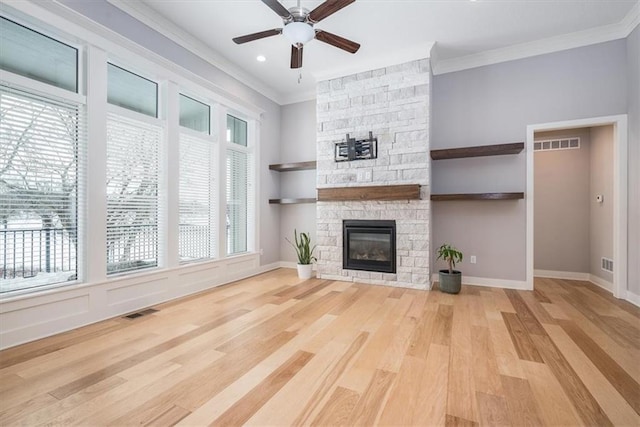 unfurnished living room with light hardwood / wood-style flooring, a stone fireplace, and crown molding