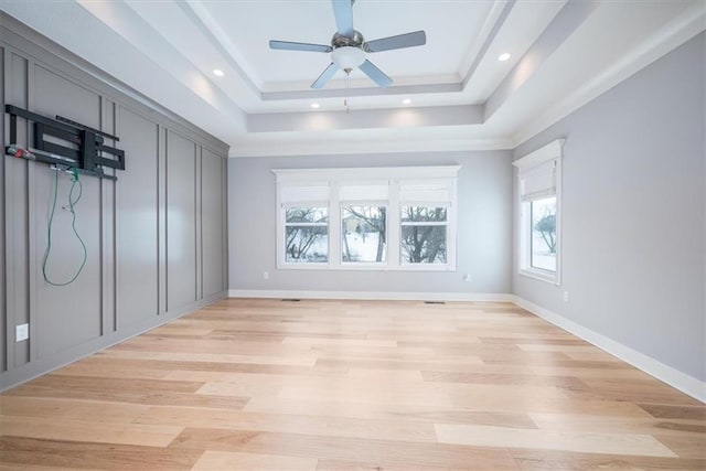 spare room with light wood-type flooring, a raised ceiling, and ceiling fan