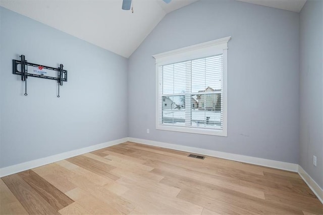 spare room with ceiling fan, vaulted ceiling, and light hardwood / wood-style flooring