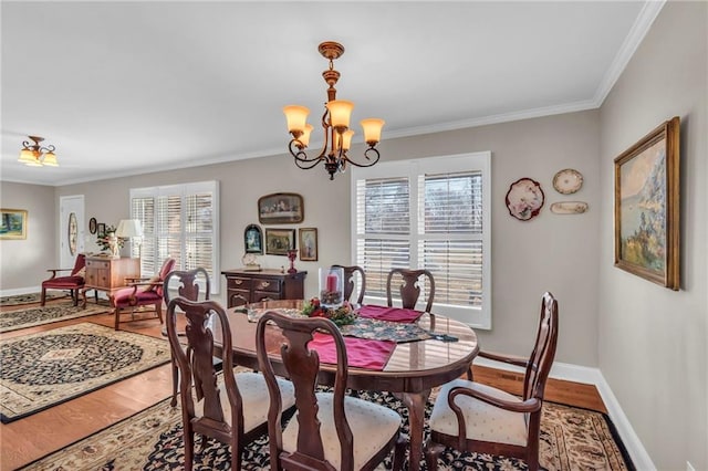 dining room with a wealth of natural light, hardwood / wood-style floors, crown molding, and an inviting chandelier