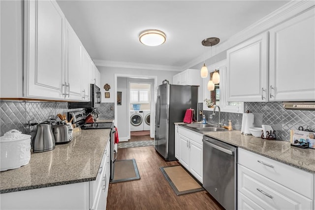 kitchen featuring pendant lighting, sink, washer and dryer, appliances with stainless steel finishes, and white cabinetry