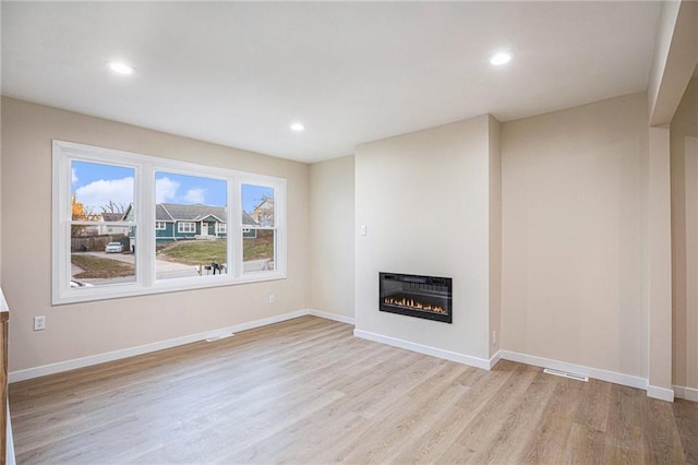 unfurnished living room featuring heating unit and light wood-type flooring