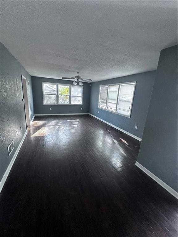 spare room with dark hardwood / wood-style floors, ceiling fan, and a textured ceiling