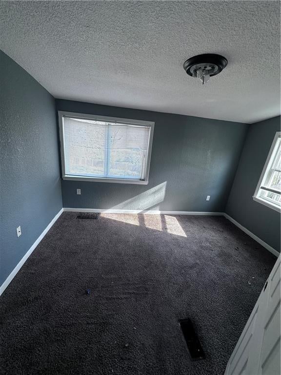 carpeted empty room featuring a textured ceiling