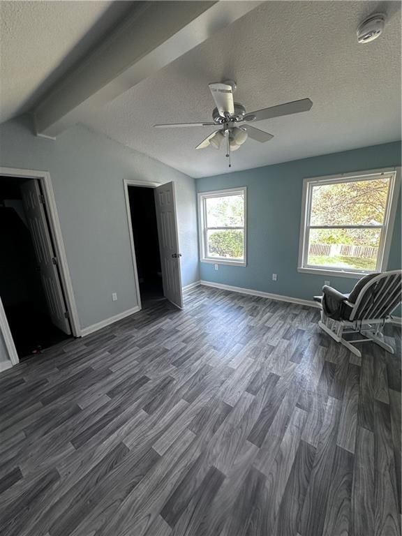 interior space featuring beamed ceiling, a textured ceiling, dark hardwood / wood-style floors, and ceiling fan