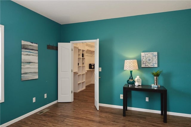 bedroom featuring dark wood-type flooring and a walk in closet