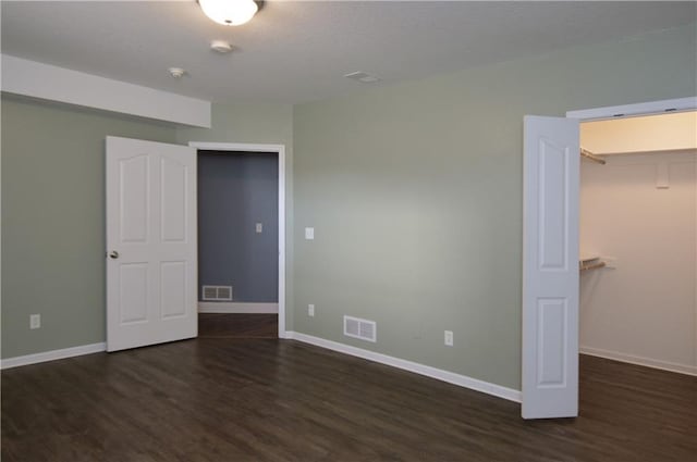 unfurnished bedroom with dark hardwood / wood-style floors, a spacious closet, and a closet