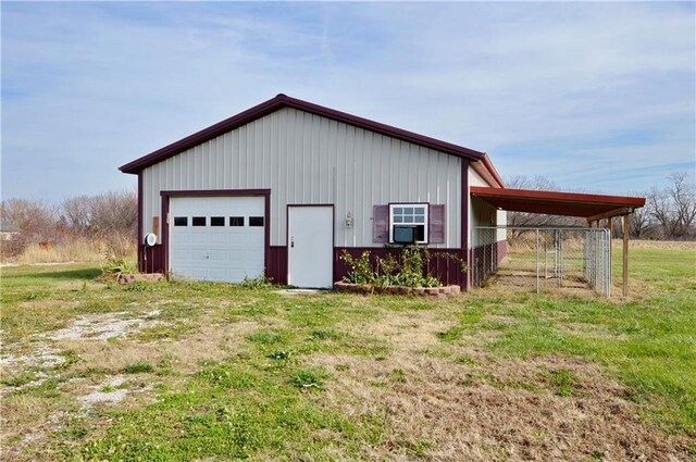 view of outdoor structure featuring a garage, a carport, and a lawn