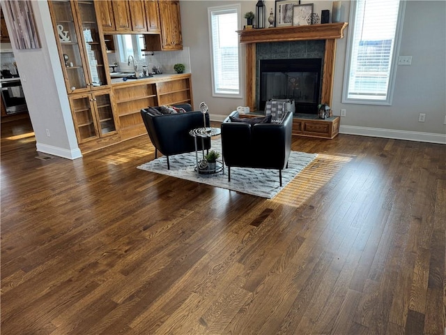 living room featuring a tiled fireplace, sink, and dark hardwood / wood-style floors