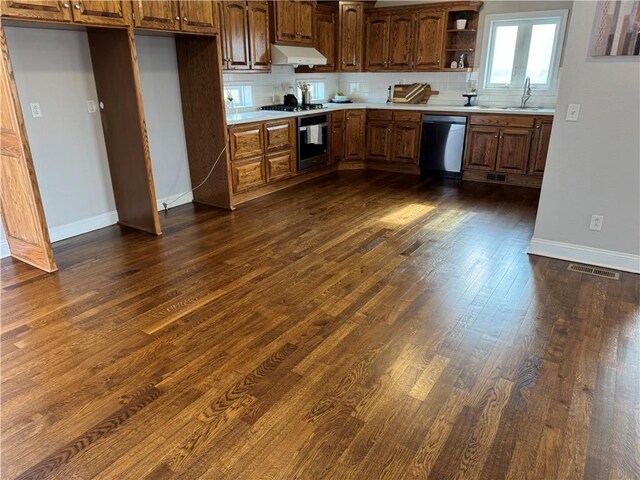 kitchen with tasteful backsplash, sink, dark hardwood / wood-style flooring, stainless steel dishwasher, and range