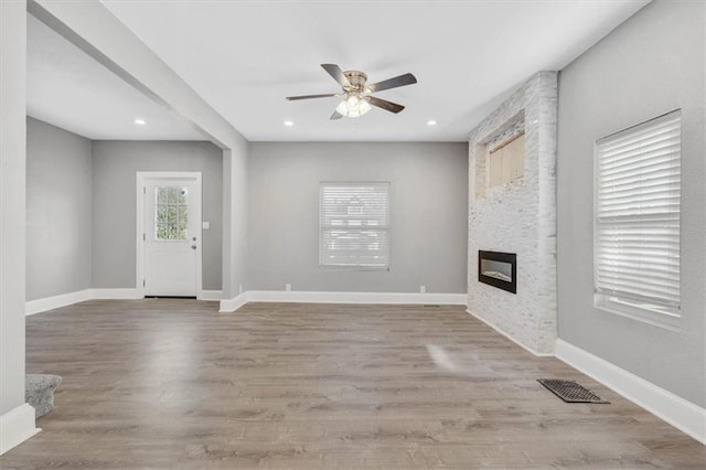 unfurnished living room featuring ceiling fan, a fireplace, and light hardwood / wood-style flooring