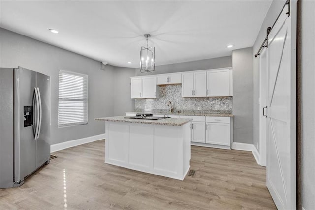 kitchen with white cabinetry, a barn door, pendant lighting, a kitchen island, and appliances with stainless steel finishes