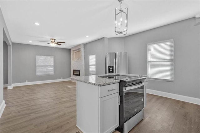 kitchen featuring light hardwood / wood-style floors, a healthy amount of sunlight, pendant lighting, and appliances with stainless steel finishes