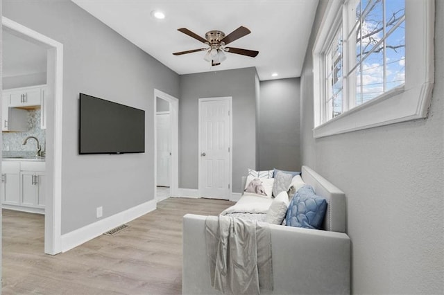 living room with ceiling fan, light wood-type flooring, and sink