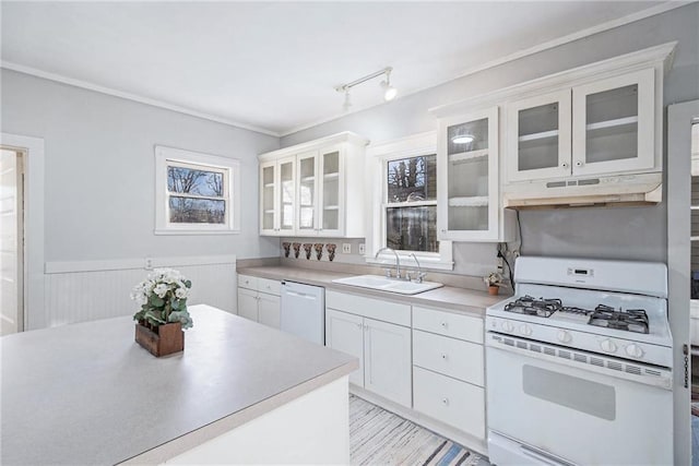 kitchen with wood walls, white cabinetry, white appliances, and sink