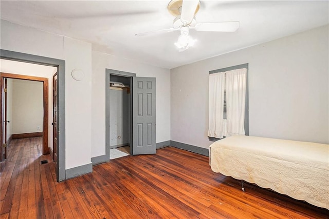 unfurnished bedroom with ceiling fan and dark wood-type flooring