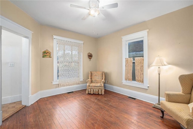 sitting room with wood-type flooring, baseboards, ceiling fan, and visible vents