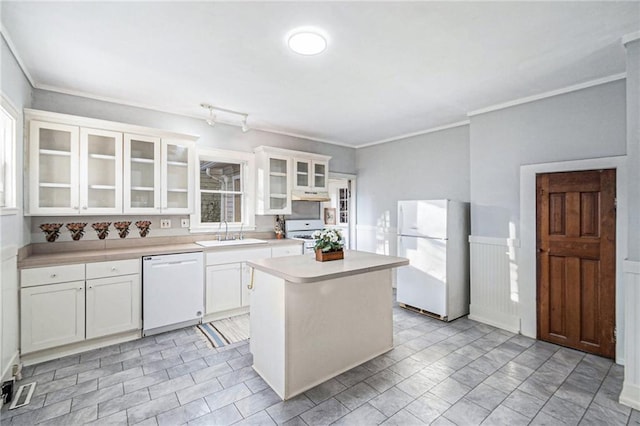 kitchen featuring white appliances, light countertops, white cabinets, under cabinet range hood, and a sink