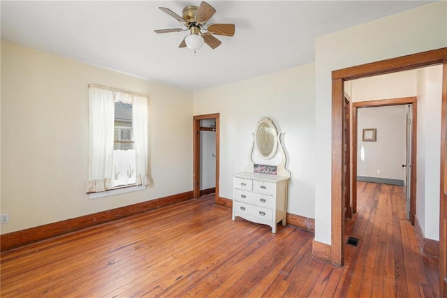 unfurnished bedroom with wood-type flooring, visible vents, baseboards, and a ceiling fan