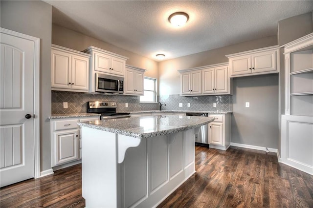 kitchen featuring light stone counters, a kitchen island, white cabinets, and appliances with stainless steel finishes