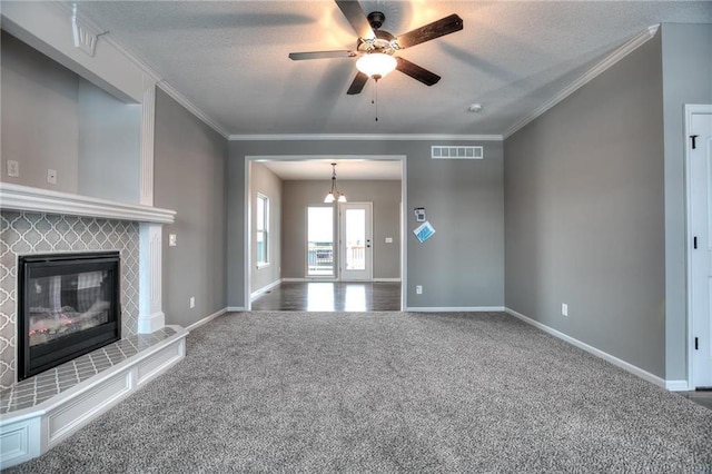 unfurnished living room featuring a tile fireplace, ceiling fan with notable chandelier, ornamental molding, a textured ceiling, and carpet floors