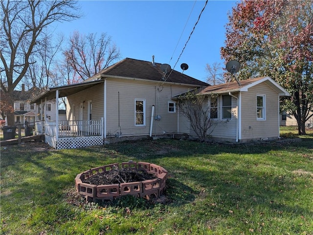 rear view of property featuring a porch and a yard