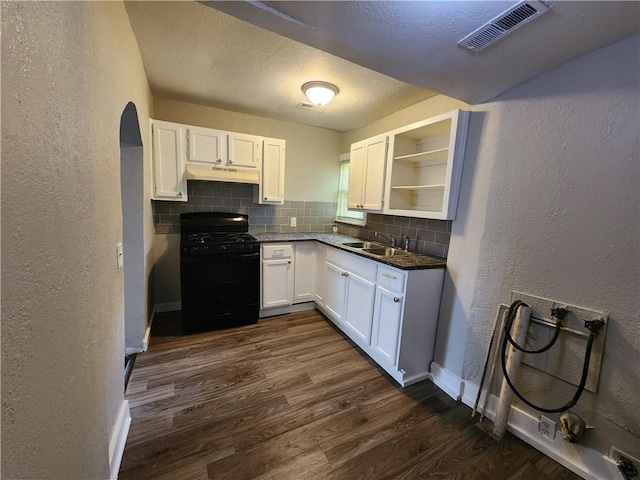 kitchen with backsplash, dark wood-type flooring, black range with gas stovetop, sink, and white cabinetry