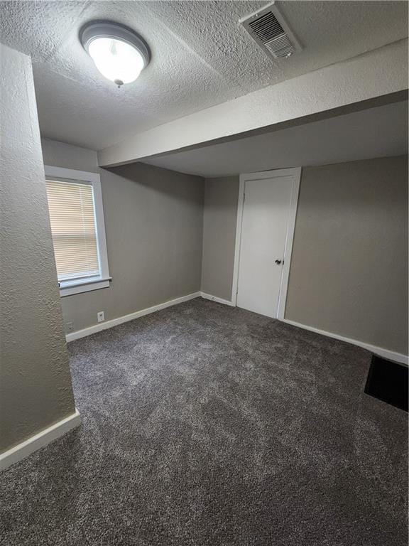 basement with a textured ceiling and dark colored carpet