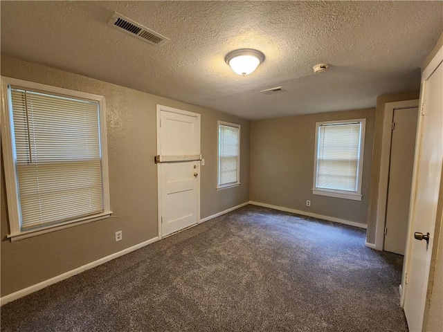 carpeted empty room with a textured ceiling