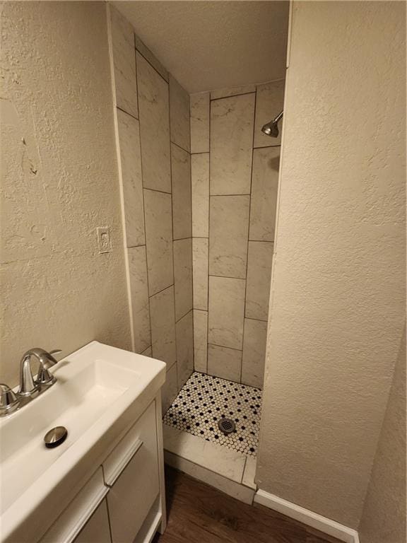 bathroom with tiled shower, wood-type flooring, and vanity