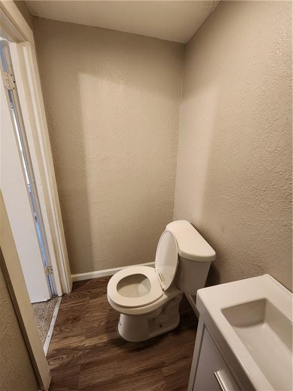 bathroom with toilet, wood-type flooring, and sink