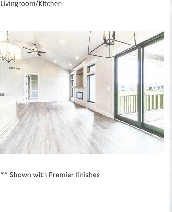 unfurnished living room with hardwood / wood-style floors, ceiling fan with notable chandelier, and lofted ceiling