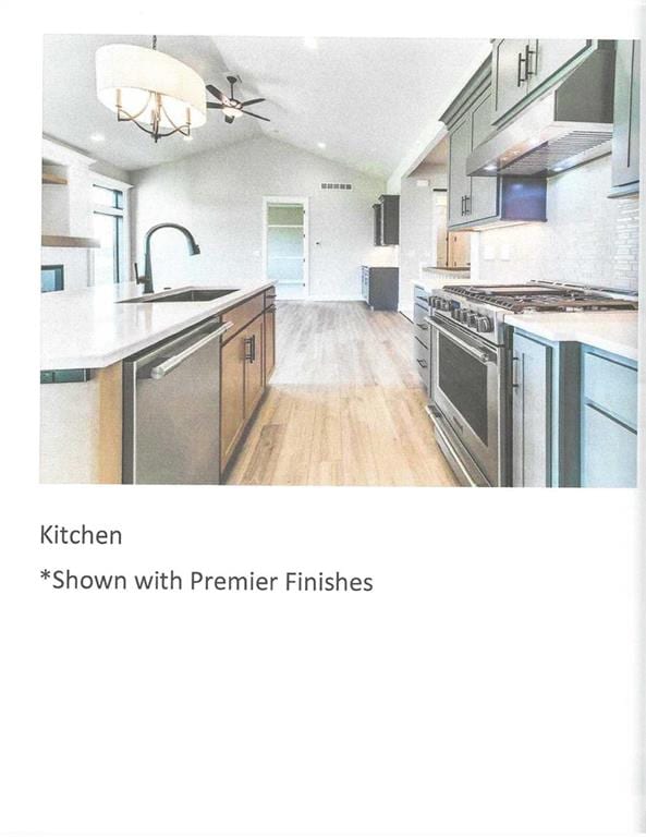 kitchen featuring ceiling fan with notable chandelier, sink, vaulted ceiling, light wood-type flooring, and stainless steel appliances