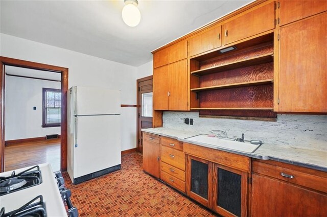 kitchen featuring white refrigerator, sink, gas range oven, and decorative backsplash