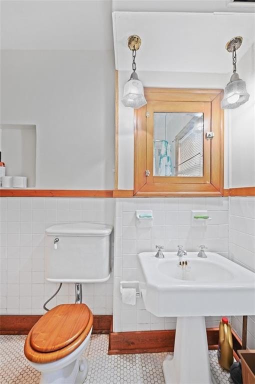 bathroom with wainscoting, tile walls, toilet, and tile patterned floors