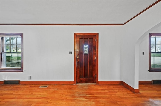 empty room with crown molding and light hardwood / wood-style flooring