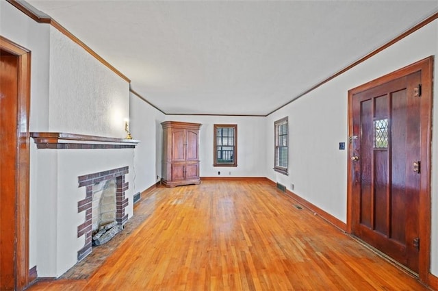 unfurnished living room featuring crown molding, light hardwood / wood-style floors, and a brick fireplace