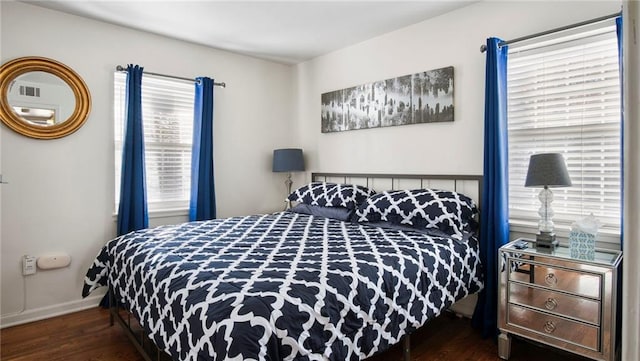 bedroom featuring multiple windows and dark hardwood / wood-style flooring