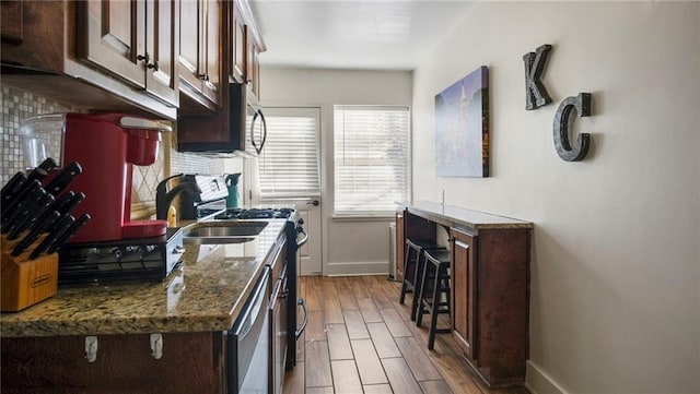 kitchen with dark stone countertops, appliances with stainless steel finishes, and light wood-type flooring