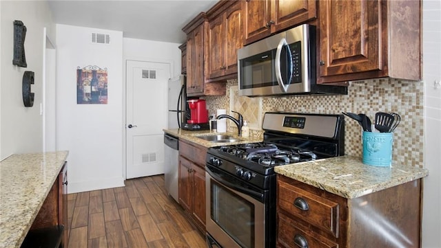 kitchen featuring appliances with stainless steel finishes, dark hardwood / wood-style flooring, tasteful backsplash, and sink