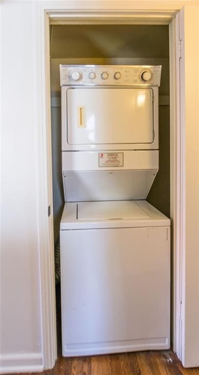 laundry room featuring dark hardwood / wood-style flooring and stacked washer and clothes dryer