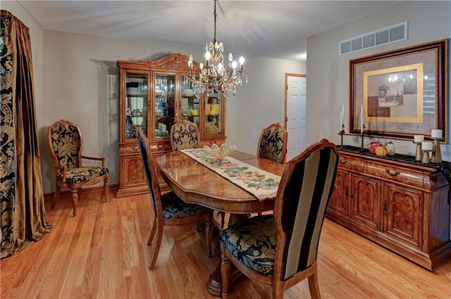 dining area with a notable chandelier and light hardwood / wood-style flooring