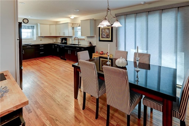 dining room with a notable chandelier, light wood-type flooring, and sink