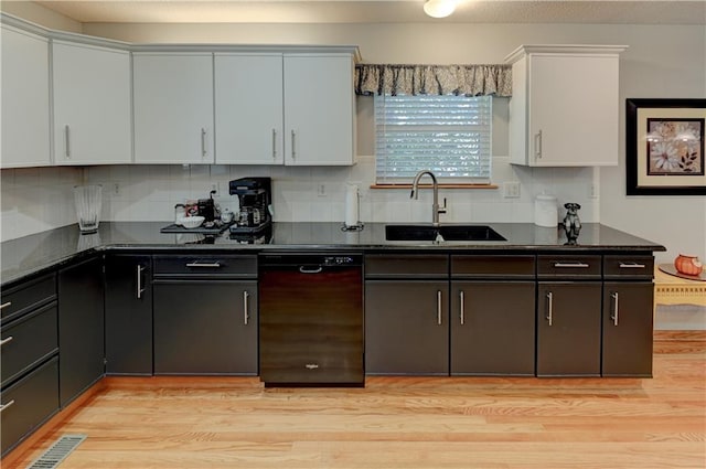 kitchen with dishwasher, white cabinets, sink, dark stone countertops, and light hardwood / wood-style floors