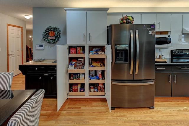 kitchen featuring tasteful backsplash, black stove, light hardwood / wood-style floors, and stainless steel refrigerator with ice dispenser