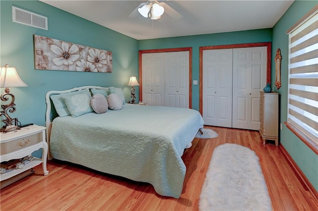 bedroom featuring ceiling fan, hardwood / wood-style floors, and two closets