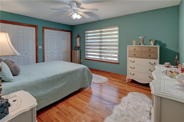 bedroom featuring light hardwood / wood-style flooring, ceiling fan, and multiple closets